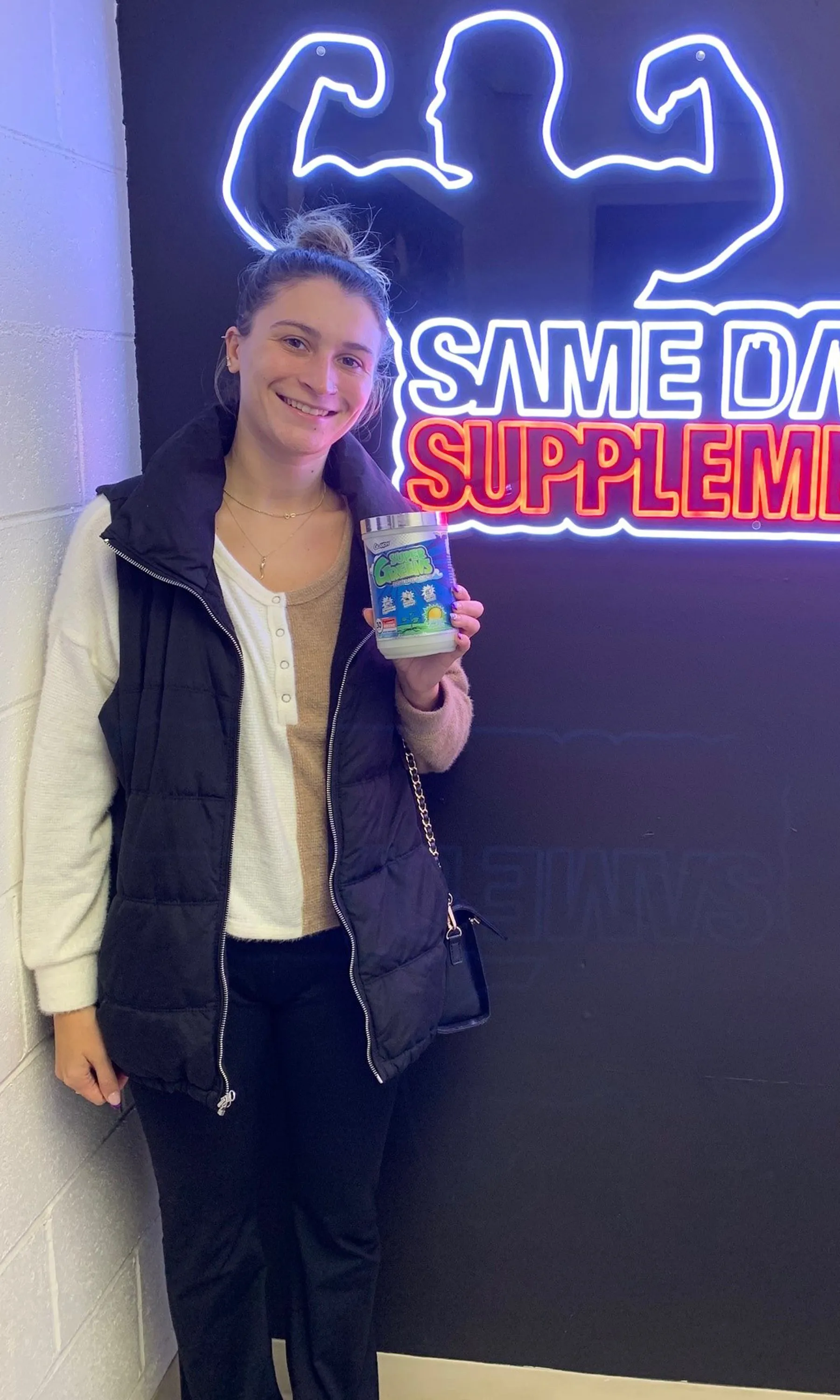 Customer smiling with GHOST Greens powder at pickup area
