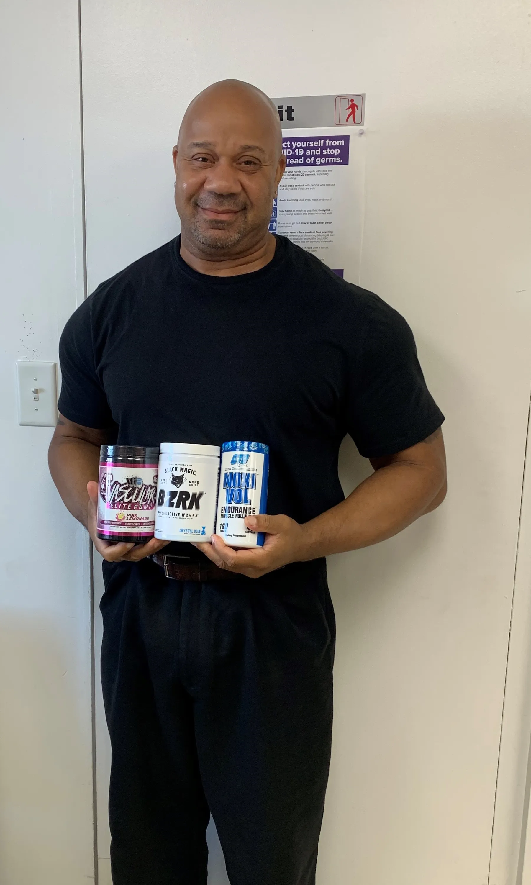 Customer holding three tubs of pre-workout supplements